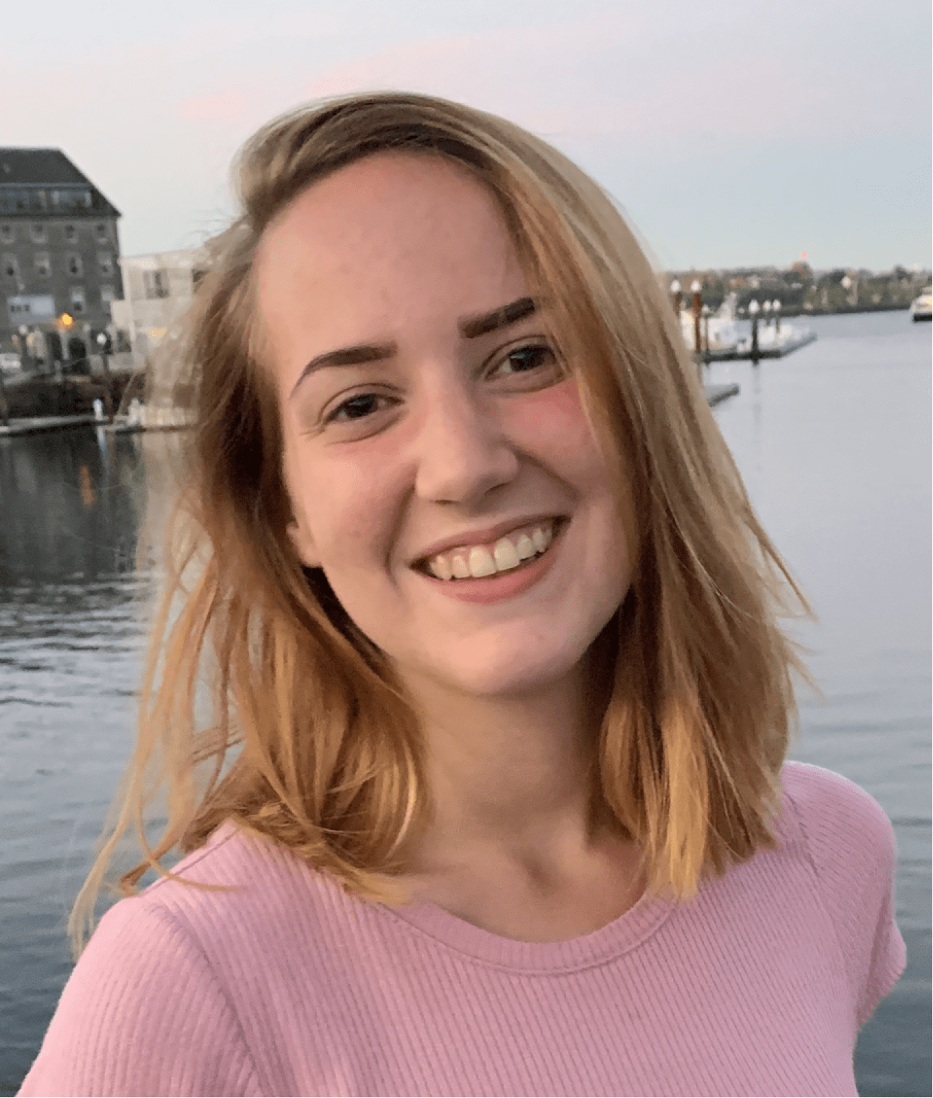 blond-haired young woman in front of a body of water