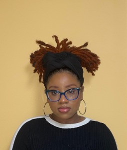 Image of a woman with stylish dreadlocks and trendy glasses.