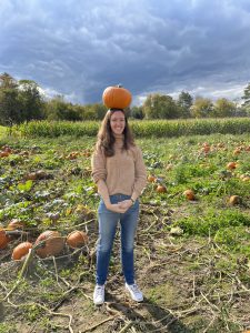 Erin Kelly photo, in a pumpkin patch with a pumpkin balanced on her head